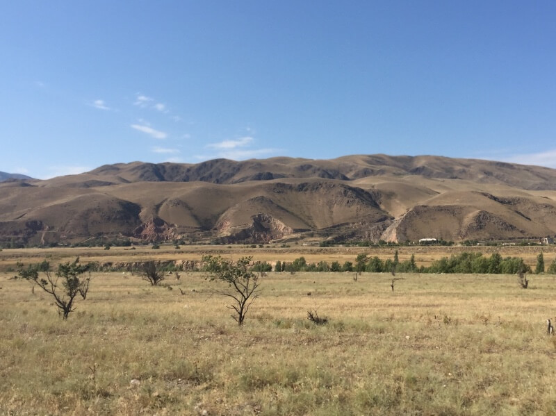 Flat plain of Kyrgyzstan surrounded by mountains
