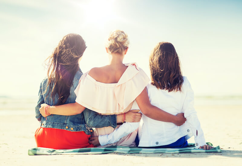 Female travel buddies with arms around one another