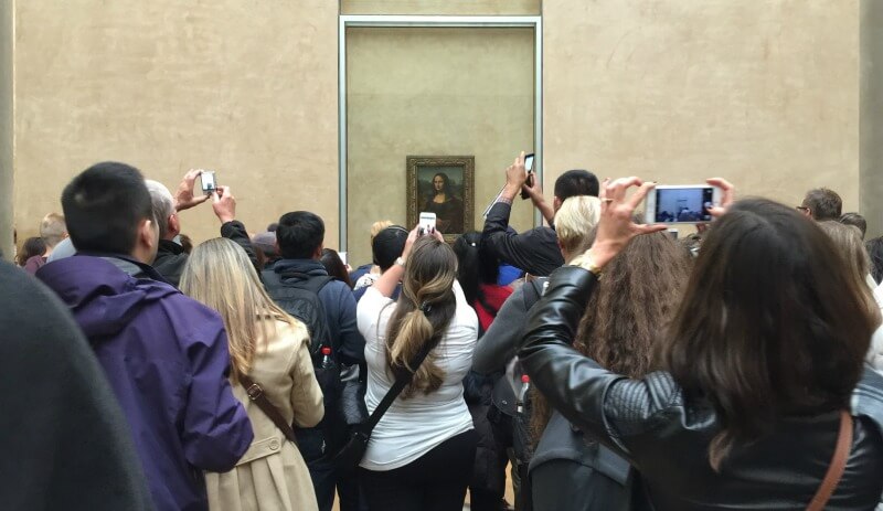 Tourists crowding around the Mona Lisa in the Louvre Museum, Paris