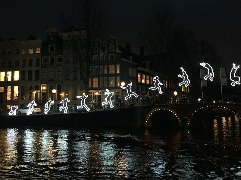 Traveling solo in Amsterdam at night: canals are lit up by creative art figurines