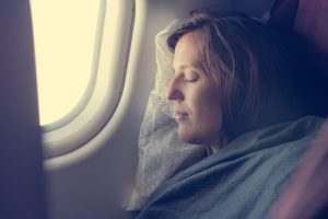 woman with travel blanket sleeping on plane